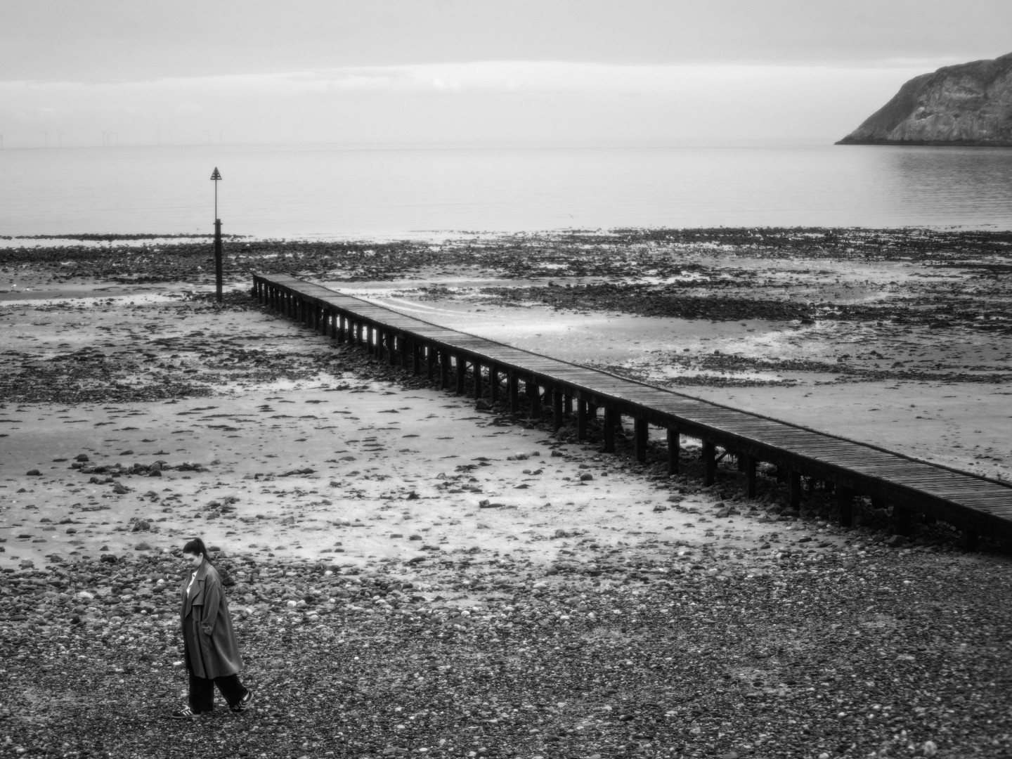 A lone woman standing by a pier at Llandudno beach