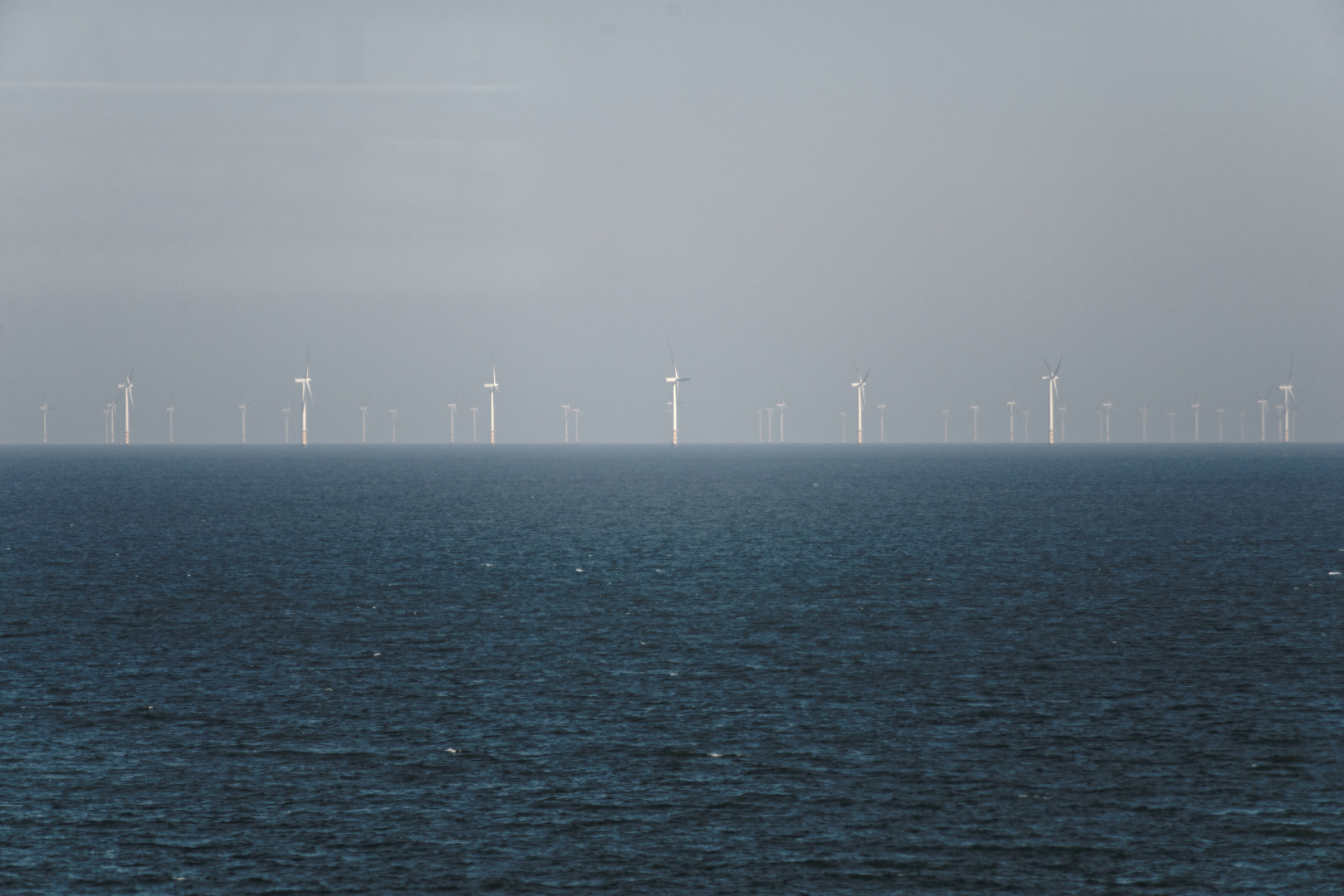 Wind turbines on the horizon between sky and sea