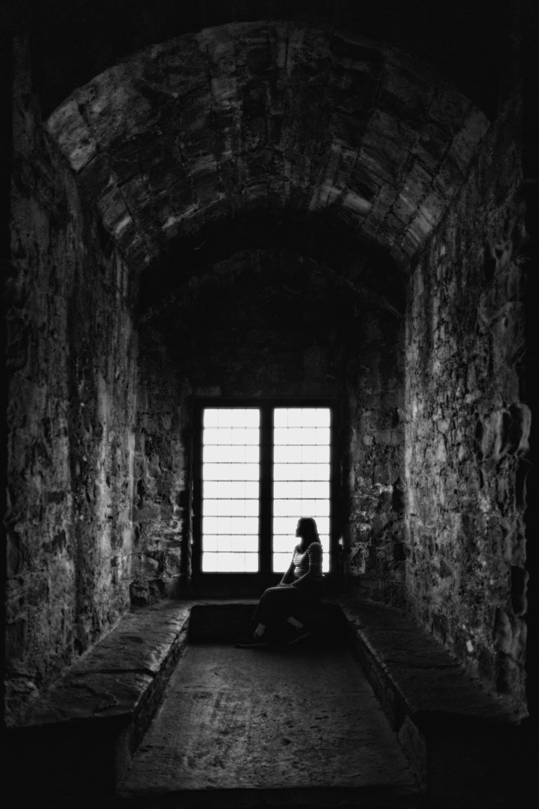 Silhouette of a person against a bright castle window